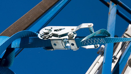 Blauer Zurrgurt an blauem Metallgestell, dahinter blauer Himmel.